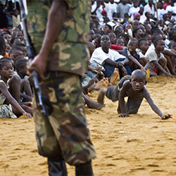 A boy from the crowd retrieves his ball in the shadow of the armed security-Jonathan Banks-finalist-EDITORIAL-War / Conflict -2917